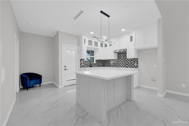 kitchen with white cabinetry, a center island, a chandelier, pendant lighting, and decorative backsplash