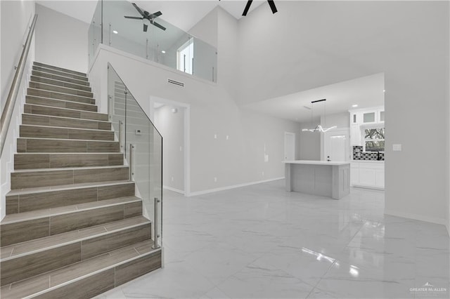 stairs with ceiling fan and a high ceiling