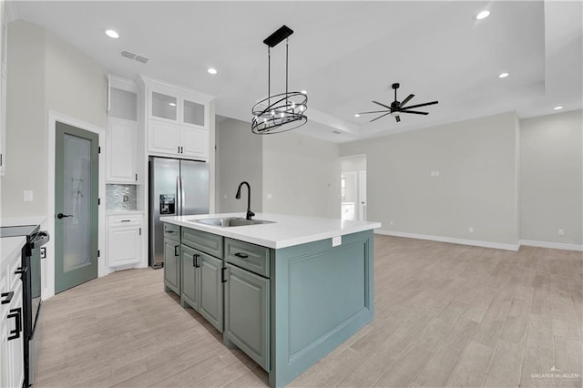 kitchen featuring stainless steel fridge, light hardwood / wood-style flooring, white cabinetry, and sink