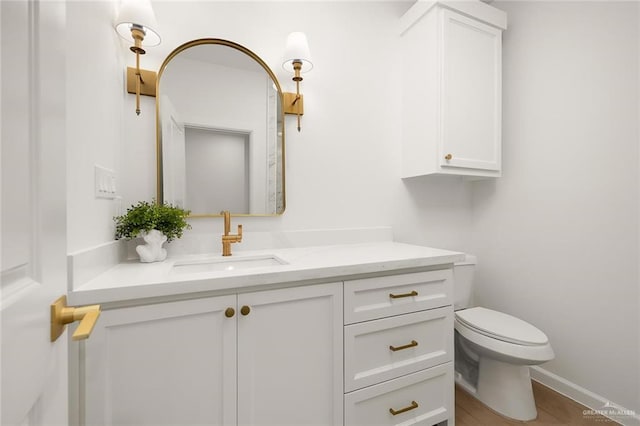 bathroom with wood-type flooring, vanity, and toilet