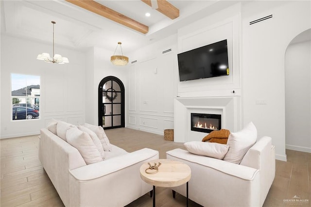 living room with a chandelier, beam ceiling, and light hardwood / wood-style flooring