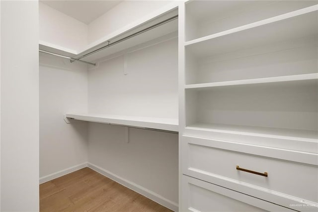 walk in closet with light hardwood / wood-style floors