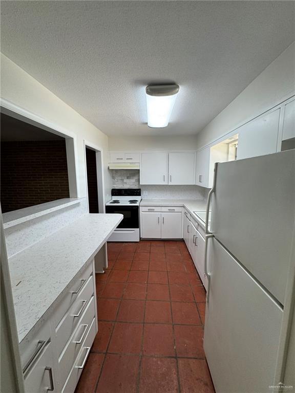kitchen featuring dark tile patterned flooring, white cabinetry, white appliances, and light countertops
