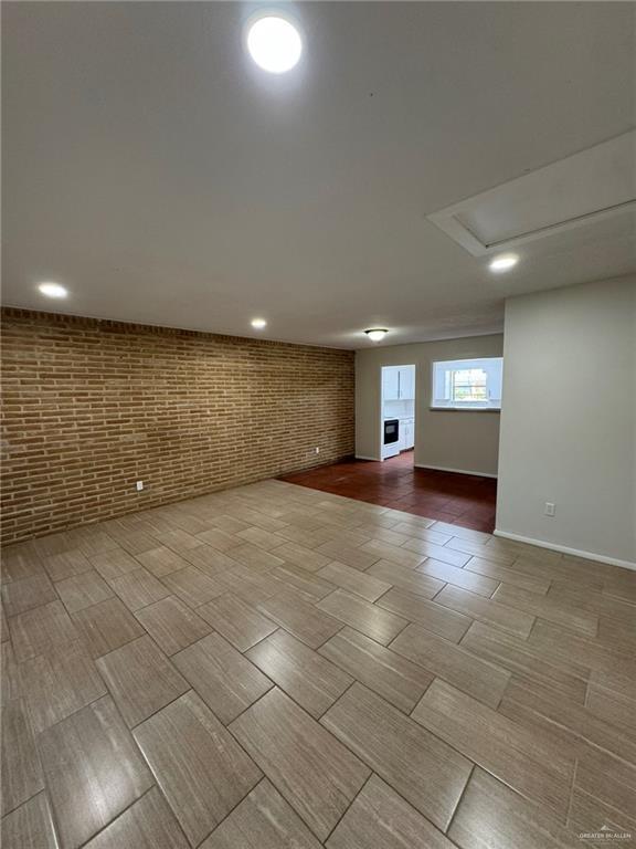 below grade area with brick wall, baseboards, wood tiled floor, and recessed lighting