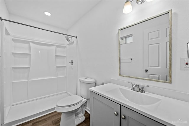 bathroom featuring hardwood / wood-style flooring, vanity, toilet, and a shower