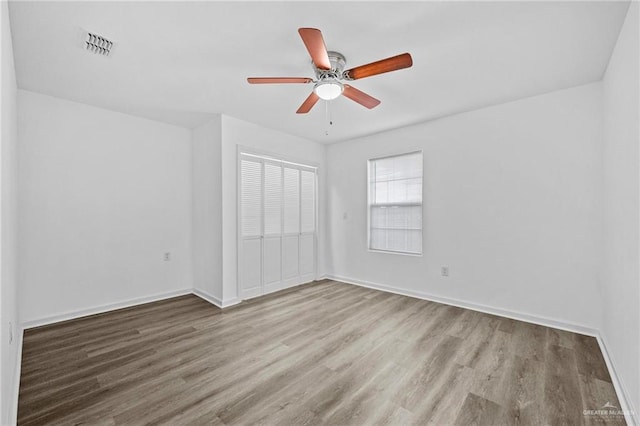 unfurnished bedroom with ceiling fan, light wood-type flooring, and a closet