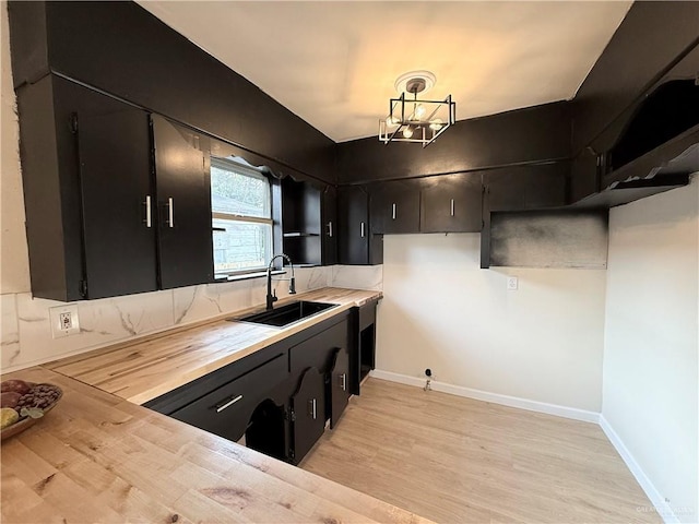 603 Witmer St, Weslaco, TX 78596 - kitchen featuring a sink, dark cabinetry, light wood-type flooring, and baseboards