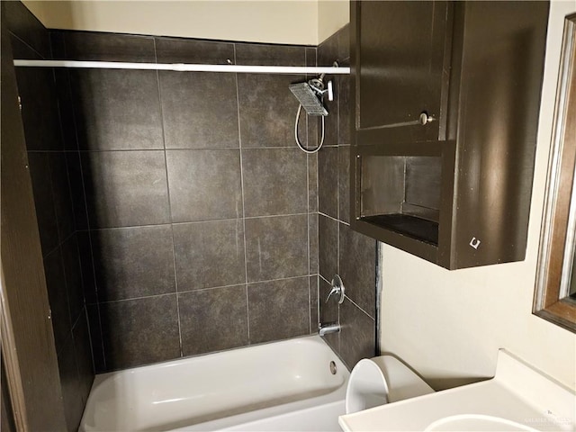 bathroom featuring tiled shower / bath combo and toilet