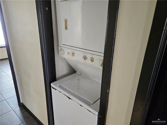 clothes washing area featuring stacked washer / dryer and tile patterned flooring