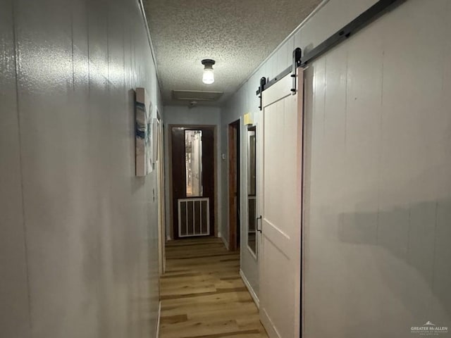 1308 E 2nd St, Weslaco, TX 78596 - corridor with light wood-type flooring, a textured ceiling, and a barn door