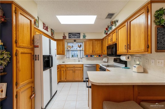 512 Mercury St, Mission, TX 78572 - kitchen with white fridge with ice dispenser, stainless steel dishwasher, range with electric stovetop, black microwave, and a peninsula