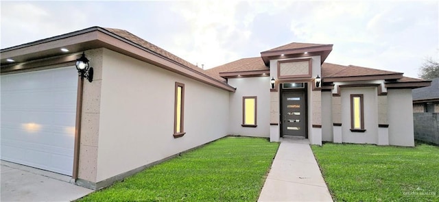 view of front of property featuring a garage, a front lawn, and stucco siding