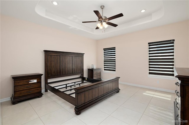 tiled bedroom with a tray ceiling and ceiling fan