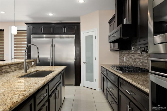 kitchen with sink, decorative backsplash, light tile patterned floors, appliances with stainless steel finishes, and decorative light fixtures