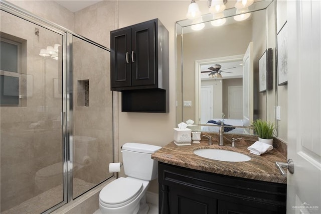 bathroom with ceiling fan, vanity, a shower with shower door, and toilet