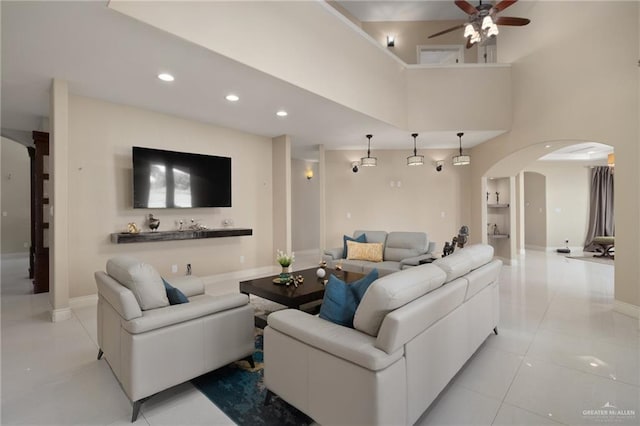 living room featuring ceiling fan, light tile patterned floors, and a towering ceiling