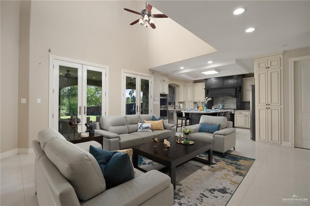 tiled living room featuring ceiling fan, french doors, and a towering ceiling