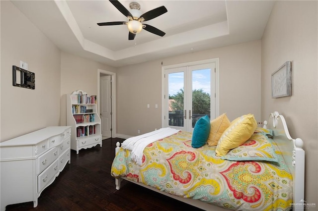 bedroom featuring a tray ceiling, access to exterior, ceiling fan, and dark hardwood / wood-style floors