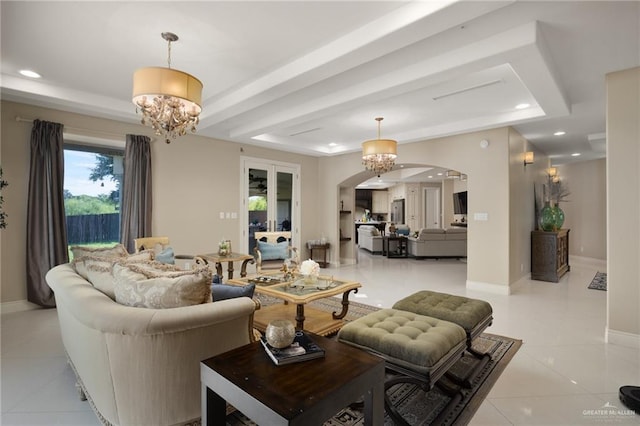 tiled living room with a chandelier, french doors, and a tray ceiling