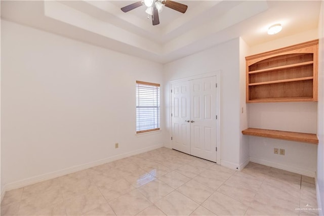 unfurnished bedroom featuring baseboards, a raised ceiling, a closet, and ceiling fan