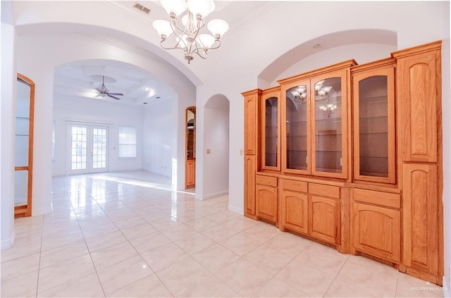 interior space featuring baseboards, light tile patterned floors, ceiling fan with notable chandelier, french doors, and arched walkways