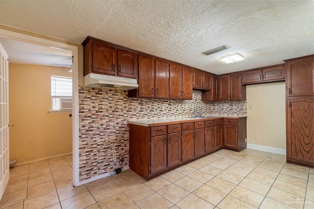 1106 17th St, Mcallen, TX 78501 - kitchen with under cabinet range hood, light tile patterned floors, a textured ceiling, light countertops, and cooling unit