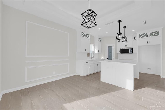 kitchen with white cabinetry, a center island, sink, and pendant lighting