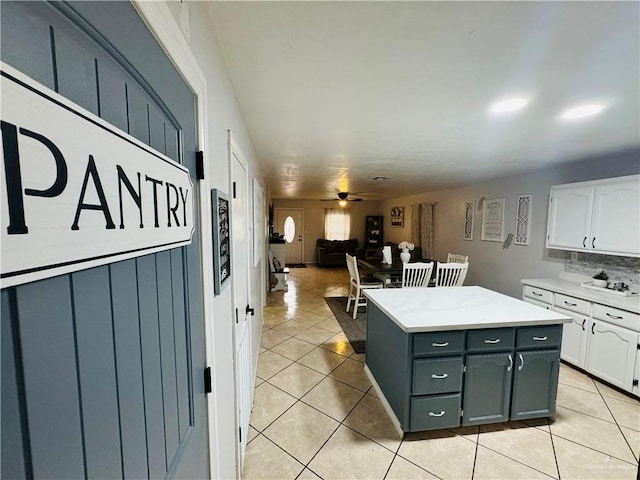 kitchen with a center island, backsplash, white cabinets, ceiling fan, and light tile patterned flooring