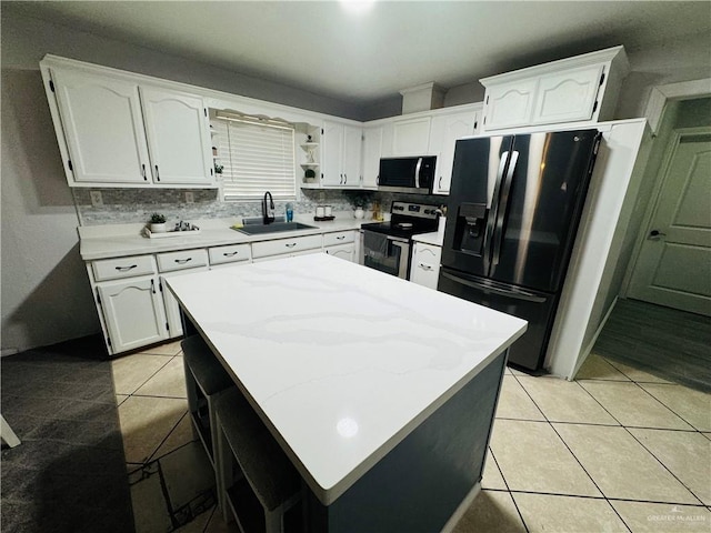 kitchen featuring appliances with stainless steel finishes, backsplash, sink, light tile patterned floors, and white cabinetry