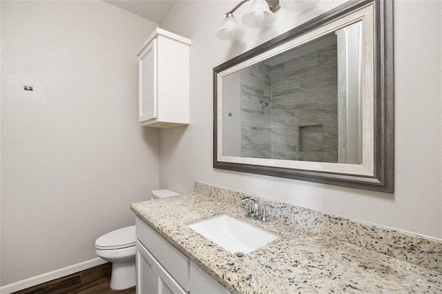1909 Taft St, Weslaco, TX 78596 - full bathroom featuring wood finished floors, a tile shower, vanity, toilet, and baseboards