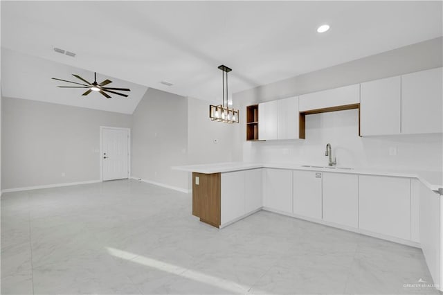 kitchen with a peninsula, light countertops, a sink, and visible vents