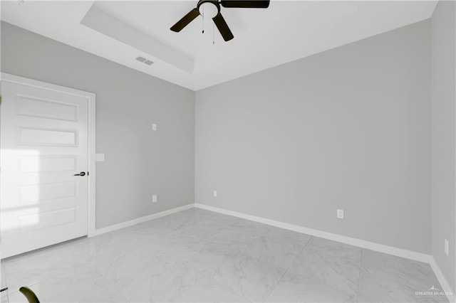 empty room featuring marble finish floor, a raised ceiling, visible vents, and baseboards