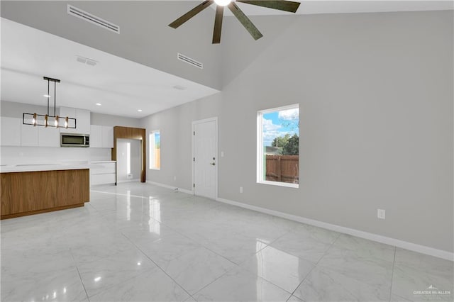 unfurnished living room with marble finish floor, plenty of natural light, visible vents, and baseboards