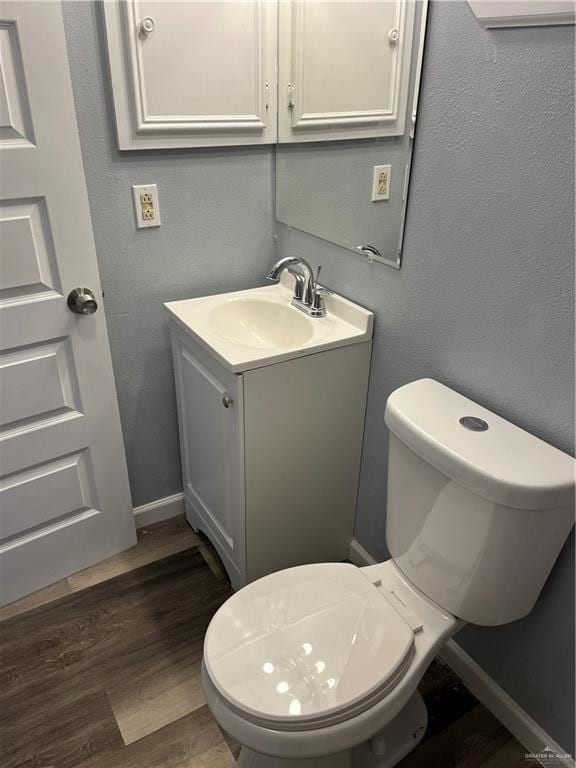 306 W 3rd St, San Juan, TX 78589 - half bathroom with vanity, baseboards, toilet, and wood finished floors