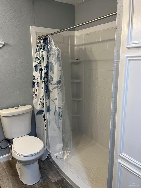306 W 3rd St, San Juan, TX 78589 - full bath with a stall shower, wood finished floors, and toilet