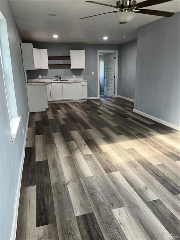 306 W 3rd St, San Juan, TX 78589 - kitchen featuring baseboards, ceiling fan, white cabinetry, a sink, and dark wood finished floors