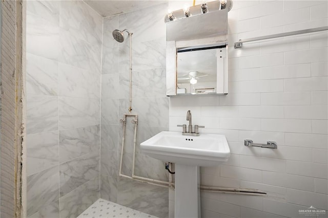 bathroom with a tile shower, tile walls, and ceiling fan