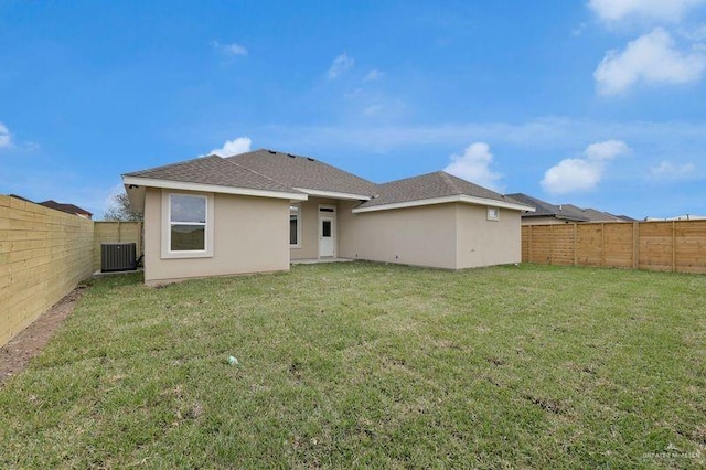 rear view of house with central AC unit and a lawn