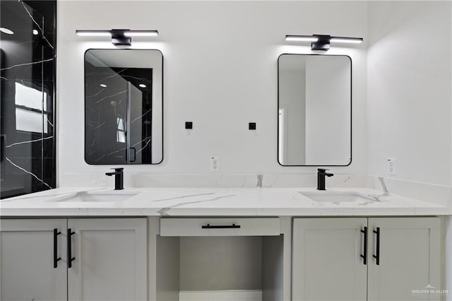 full bathroom with a sink, a marble finish shower, and double vanity