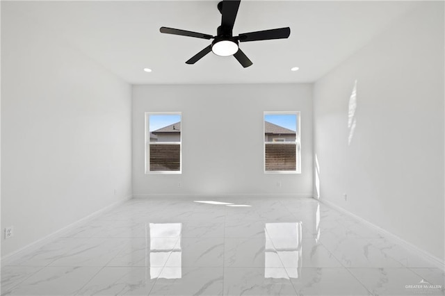 empty room featuring marble finish floor, recessed lighting, and baseboards