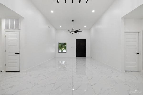 empty room with ceiling fan and a high ceiling