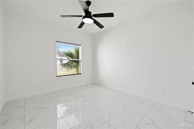 spare room with marble finish floor, ceiling fan, and baseboards