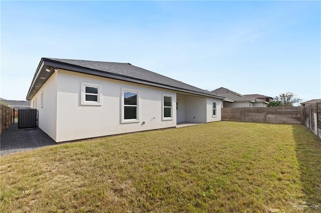 rear view of property with central AC unit, a lawn, a fenced backyard, and stucco siding