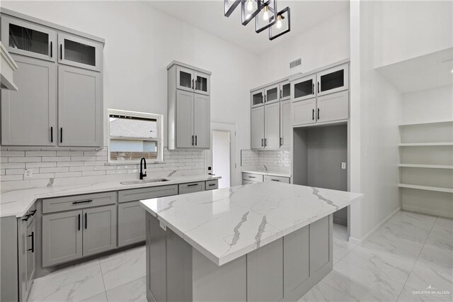 kitchen featuring light stone counters, sink, gray cabinetry, and a kitchen island