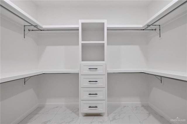 spacious closet with marble finish floor and built in desk