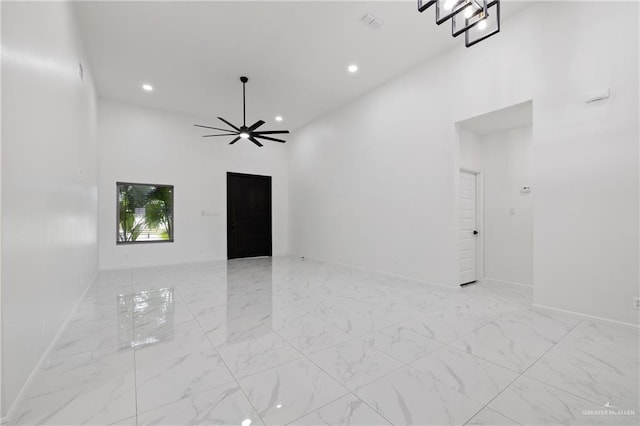 spare room featuring a towering ceiling, marble finish floor, a ceiling fan, and recessed lighting