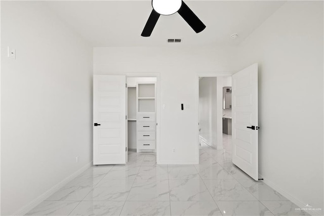 unfurnished bedroom featuring marble finish floor, a walk in closet, visible vents, and baseboards