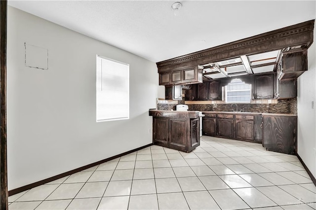 kitchen featuring backsplash, dark brown cabinets, light tile patterned flooring, and sink