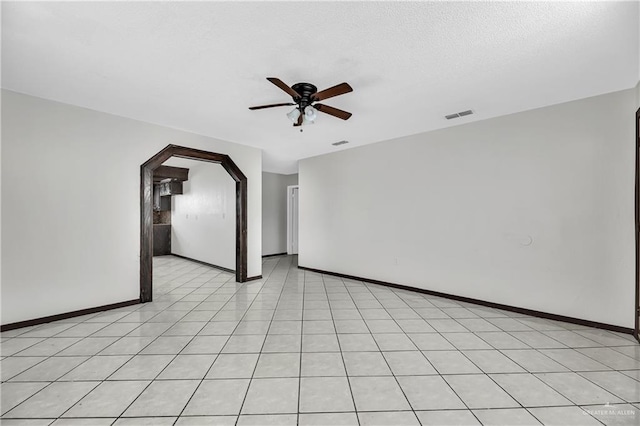 unfurnished room with ceiling fan, light tile patterned floors, and a textured ceiling