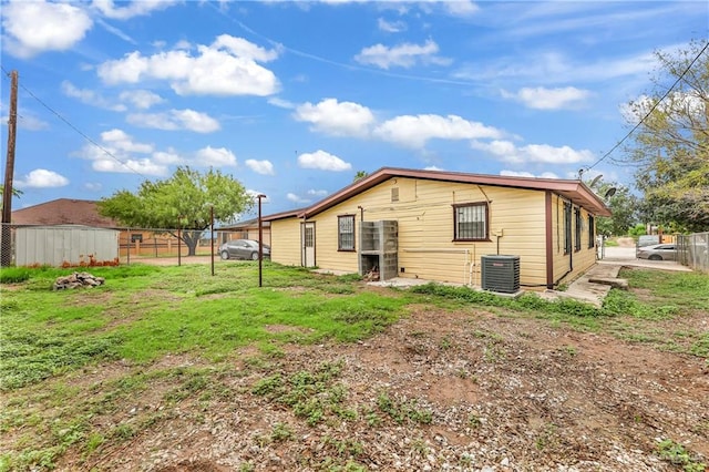 rear view of property with cooling unit and a yard